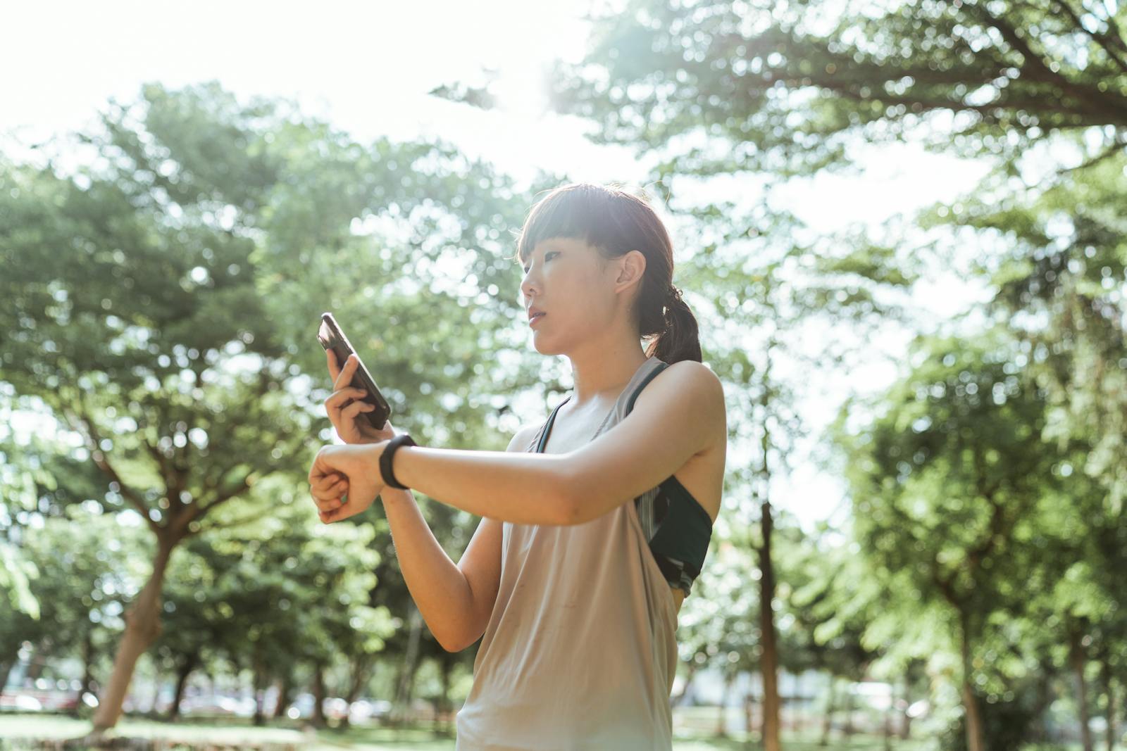 An athlete checking her smartwatch and smartphone mid-training, data syncing across both